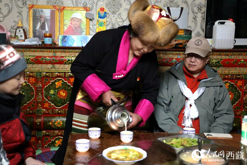 扎西曲登社区的居民在家中热情招待远道而来的游客。居民身着盛装，为游客倒上热腾腾的酥油茶，桌上摆放着切玛与特色美食，宾主共话民族团结情谊。人民网记者 吴雨仁摄