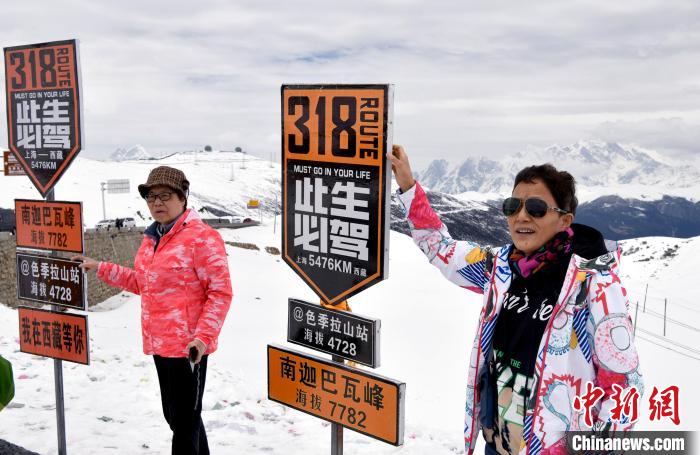 图为5月14日，西藏林芝色季拉山观景台，游客与南迦巴瓦峰合影。　李林 摄