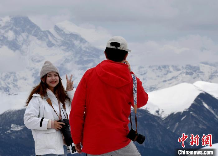 图为5月14日，西藏林芝色季拉山观景台，游客与南迦巴瓦峰合影。　　李林 摄