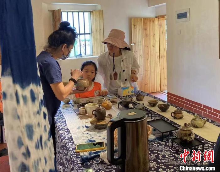 图为:游客正在咨询台湾柴烧作品。 叶秋云 摄