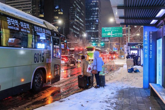 12月4日，在韩国首尔，人们在雪中候车。新华社发（朴晋泽摄）