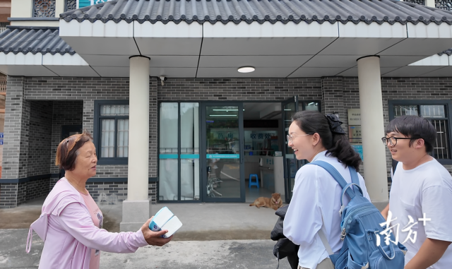 公共服务组成员王樱洁(中)和张龙(右)在崖口村卫生室前跟村民打招呼。