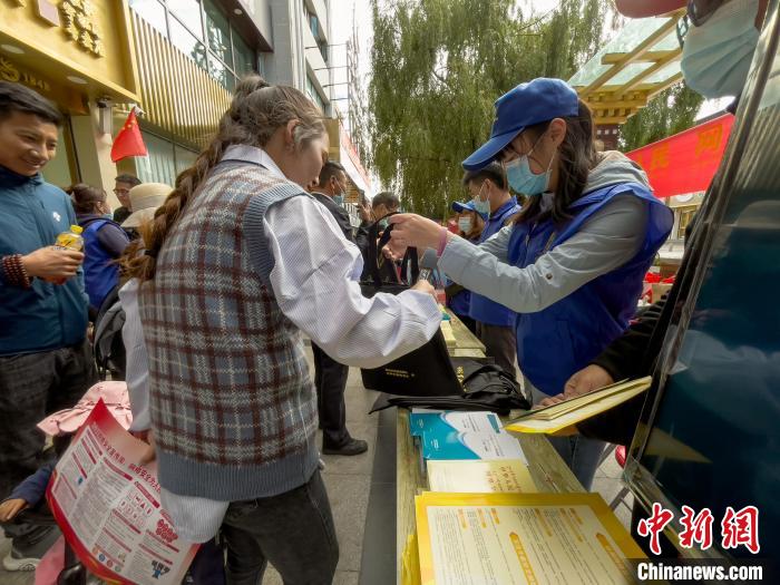 图为志愿者为市民发放网络安全宣传手册。　谢牧 摄